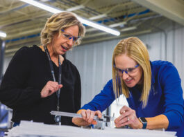 Crystal Group director of production Kara Kortenkamp and supply chain director Katie Wagner validate dimensions on a machined metal component at the company’s Hiawatha facility. CREDIT CRYSTAL GROUP manufacturing