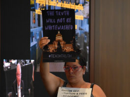 A protestor holds a sign depicting the Iowa Capitol accompanied by the words "The truth will not be whitewashed" at the Iowa Board of Regents meeting Wednesday, June 11.