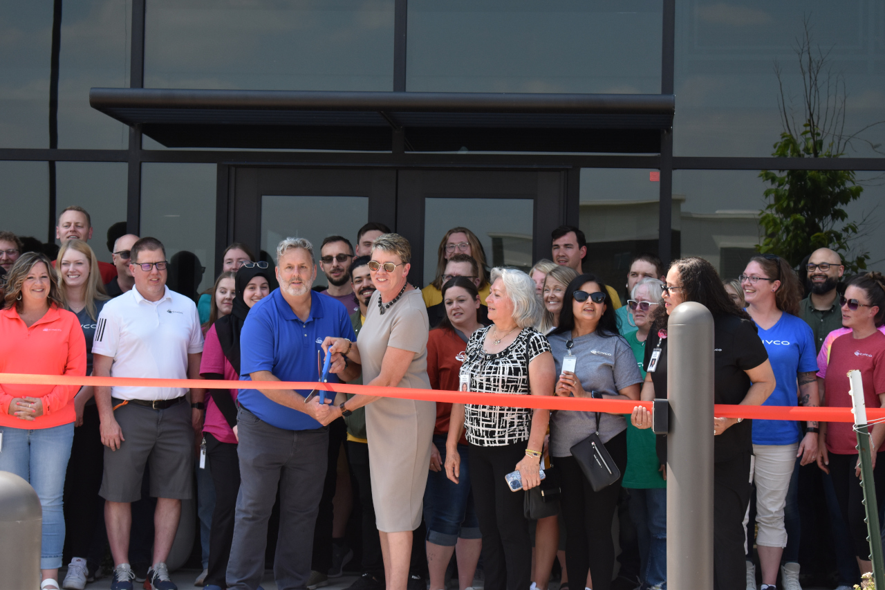 Ribbon cutting CIVCO Medical Solutions President Robin Therme (center) readies a giant pair of scissors for the ribbon-cutting ceremony celebrating the company's new facility on June 6.