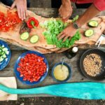 Vegetables are chopped and sliced on a rustic cutting board in preparation for cooking.