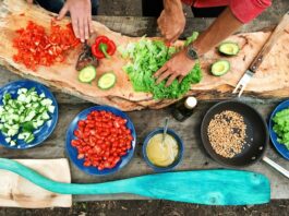 Vegetables are chopped and sliced on a rustic cutting board in preparation for cooking.