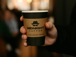 Midnight Coffee's logo is prominently displayed on a disposable coffee cup.