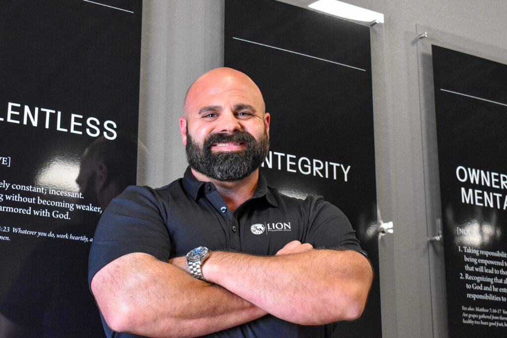 Lion Development Group owner Brandon Pratt poses in front of a wall display of the company’s core values at his headquarters in North Liberty on July 1, 2025. CREDIT ANNIE SMITH BARKALOW