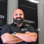 Lion Development Group owner Brandon Pratt poses in front of a wall display of the company’s core values at his headquarters in North Liberty on July 1, 2025. CREDIT ANNIE SMITH BARKALOW