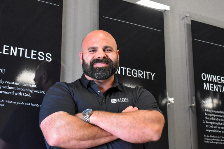 Lion Development Group owner Brandon Pratt poses in front of a wall display of the company’s core values at his headquarters in North Liberty on July 1, 2025. CREDIT ANNIE SMITH BARKALOW