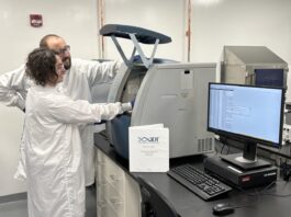 IDT quality control specialists Austin Kraff (background) and Jacob Draghicchio (foreground) load QC samples onto a Capillary Electrophoresis instrument to assess product purity.