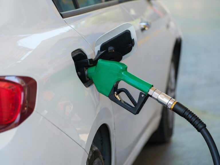The green handle of a gas pump is inserted into a car's fuel tank.