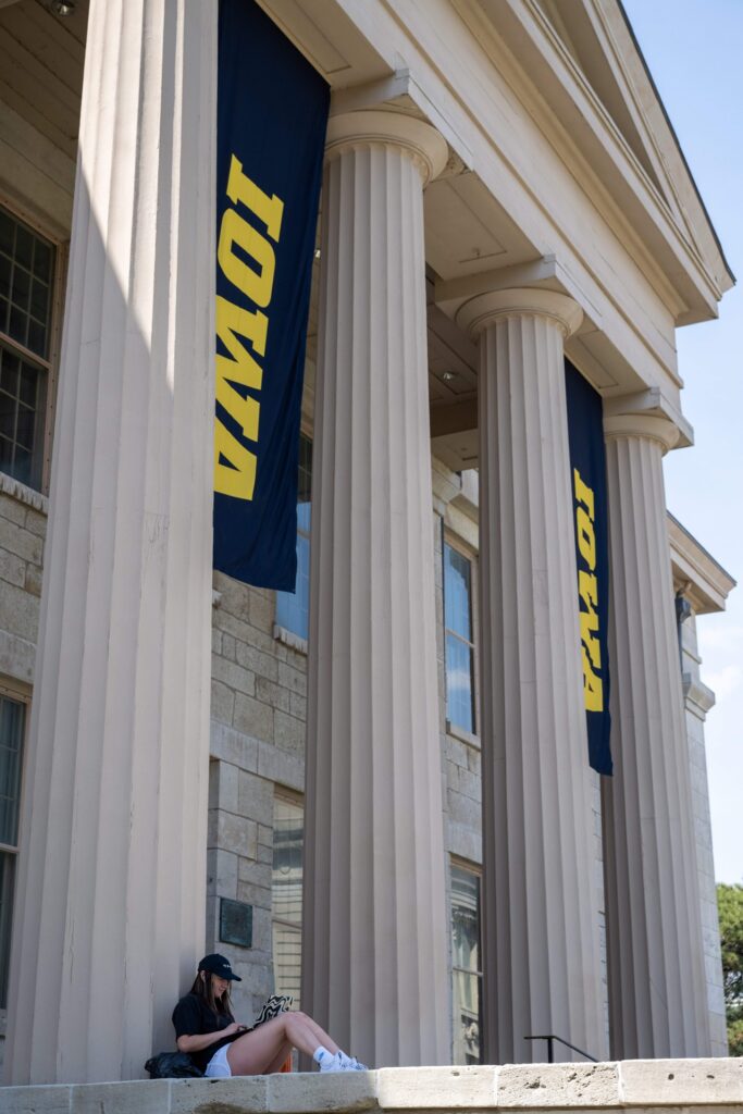 A student studies while leaning against a column of the old capitol.