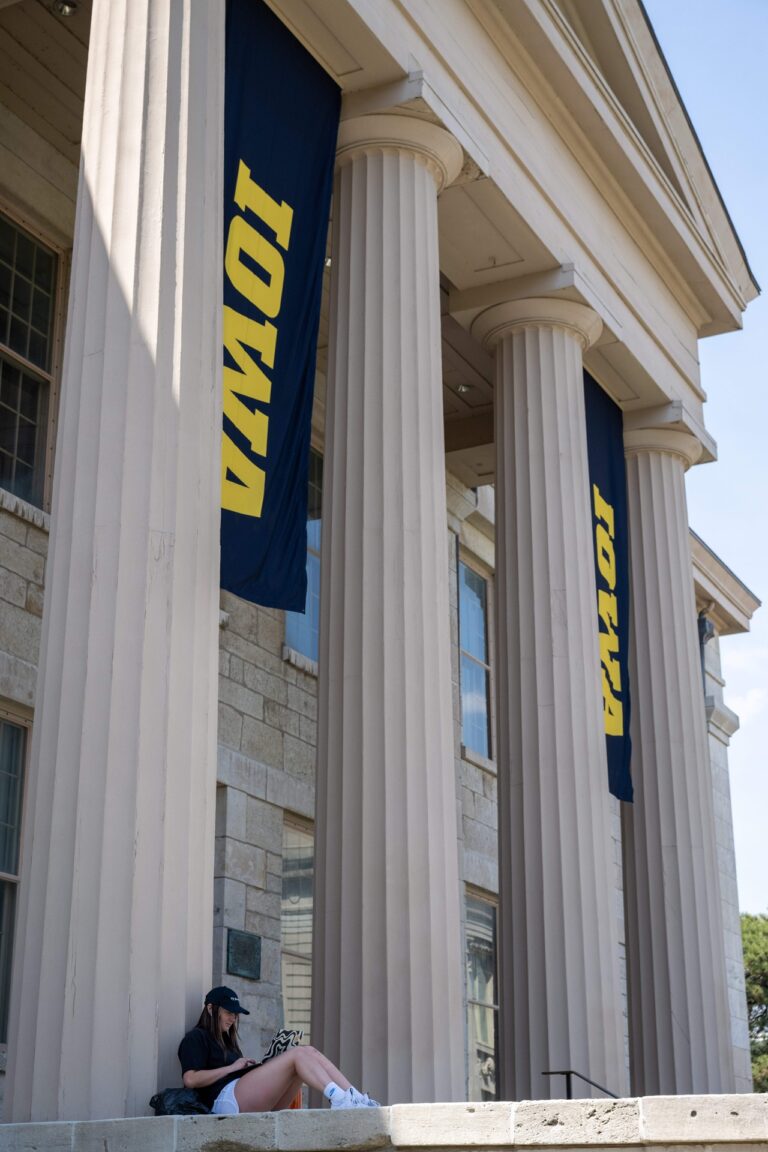 A student studies while leaning against a column of the old capitol.