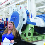 A Nordex USA employee describes one of the company’s wind turbine drivetrain assemblies during a tour of the company’s reopened plant in West Branch July 1, 2025. CREDIT RICHARD PRATT