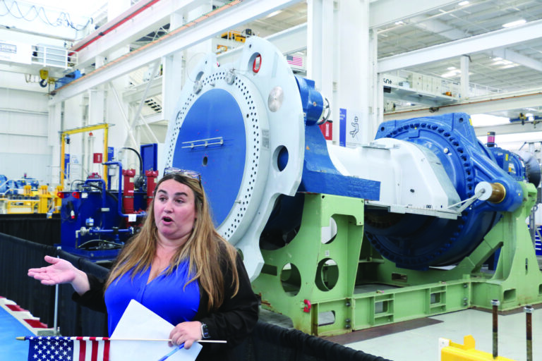 A Nordex USA employee describes one of the company’s wind turbine drivetrain assemblies during a tour of the company’s reopened plant in West Branch July 1, 2025. CREDIT RICHARD PRATT