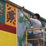 Iowa City-based artist Thomas Agran works on a mural celebrating Fairtrade Month at Coralville's New Pioneer Co-op Sept. 22, 2025.