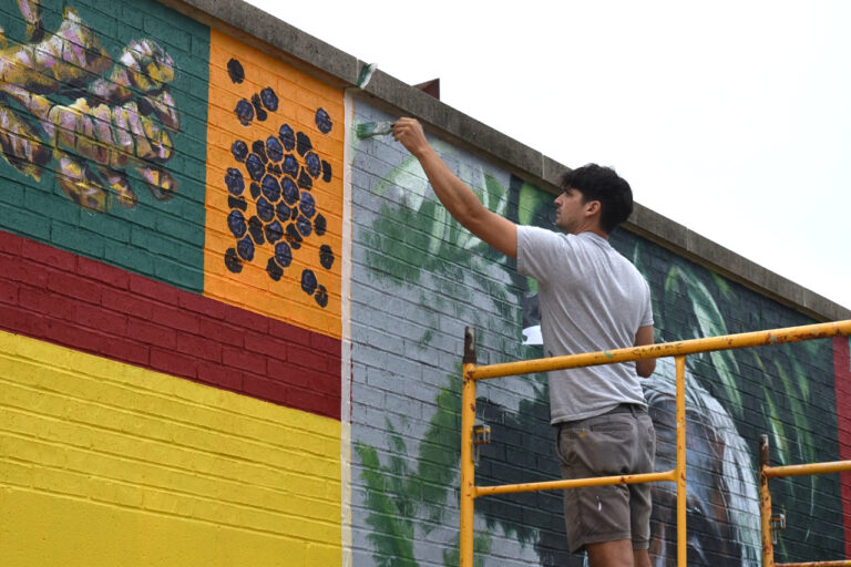 Iowa City-based artist Thomas Agran works on a mural celebrating Fairtrade Month at Coralville's New Pioneer Co-op Sept. 22, 2025.