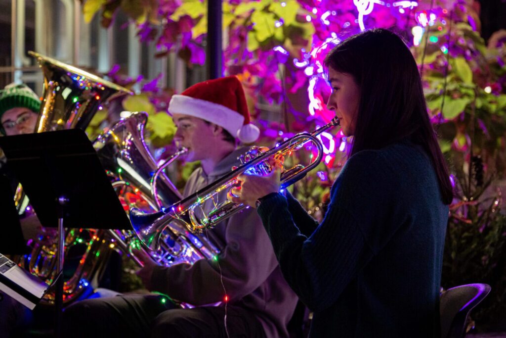 A brass band plays with Christmas lights twinkling in the background.