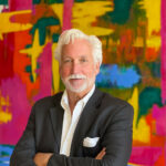 Tim Charles, photographed by his wife, Janice, stands in front of one of his paintings.