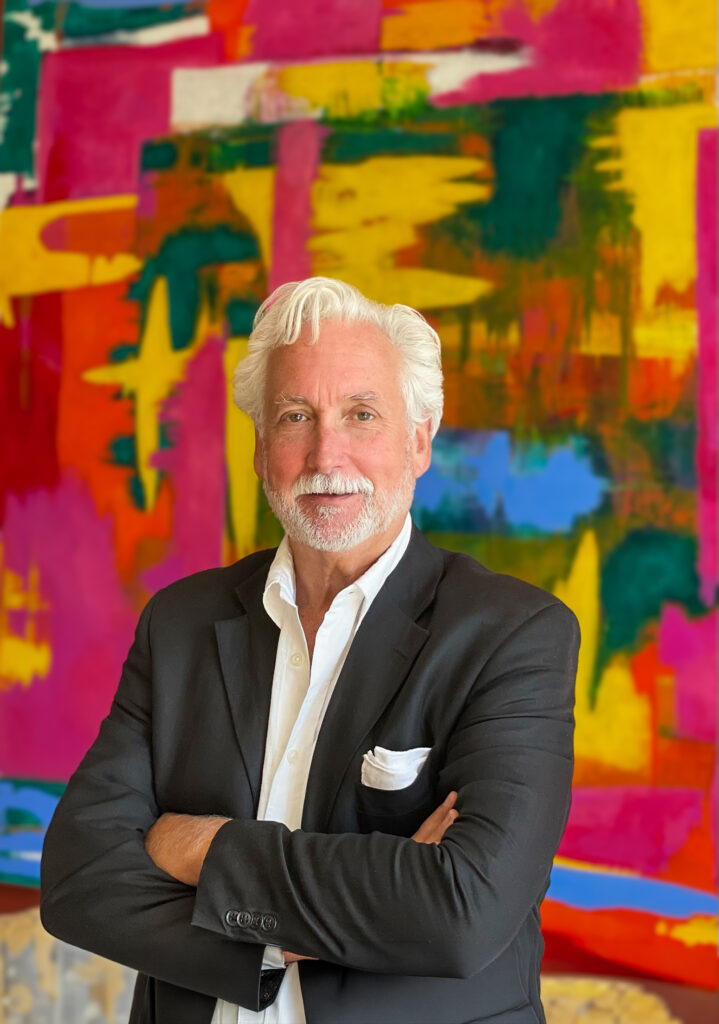 Tim Charles, photographed by his wife, Janice, stands in front of one of his paintings.